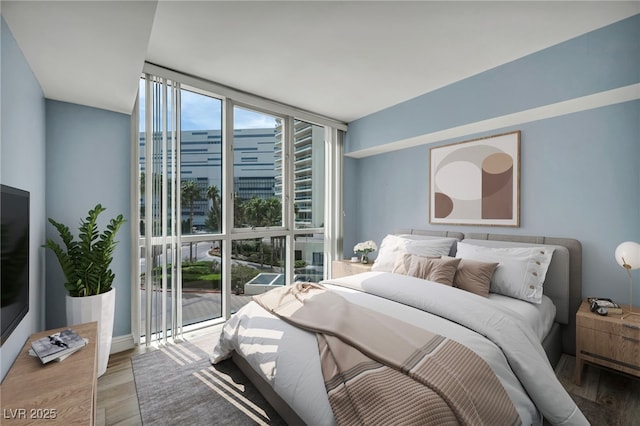 bedroom featuring a city view, floor to ceiling windows, and wood finished floors