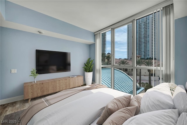 bedroom featuring baseboards, floor to ceiling windows, and wood finished floors