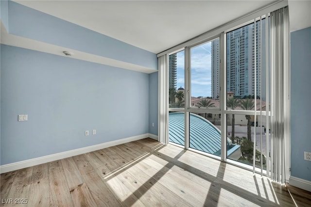 unfurnished room featuring baseboards, wood finished floors, and expansive windows