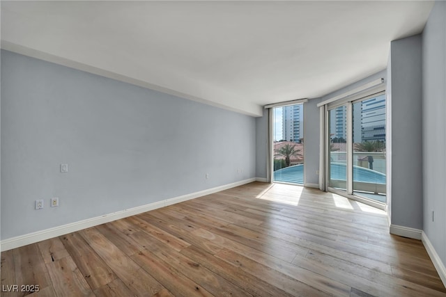 unfurnished room with baseboards and wood finished floors