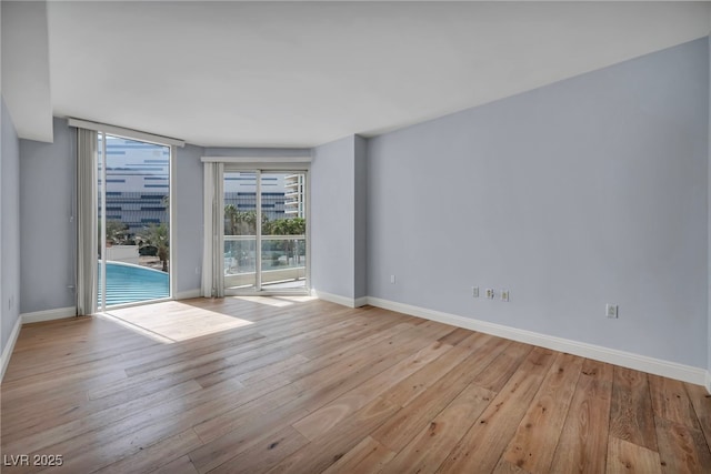 unfurnished room with baseboards and hardwood / wood-style floors