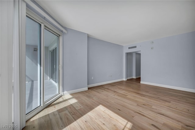 empty room with visible vents, baseboards, and wood finished floors