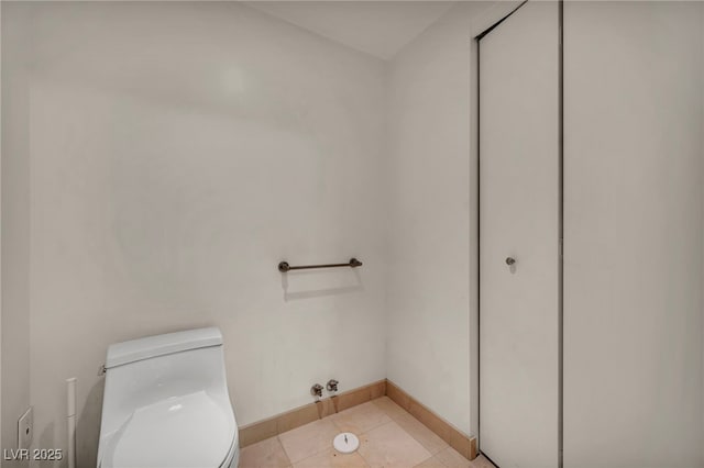 bathroom with baseboards, tile patterned floors, and toilet