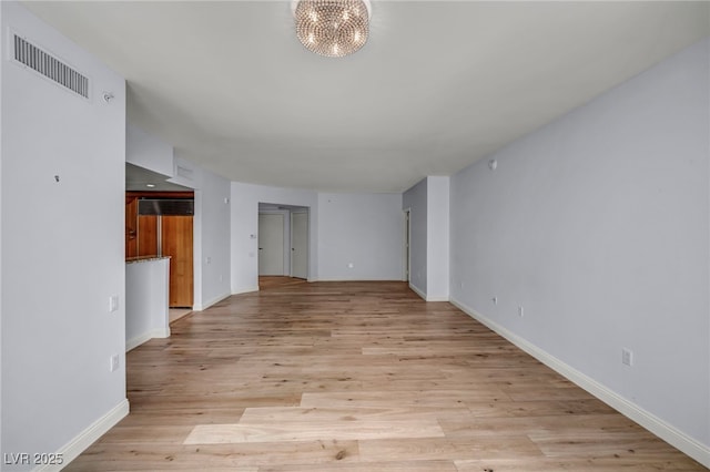 unfurnished living room with visible vents, baseboards, a notable chandelier, and light wood-type flooring