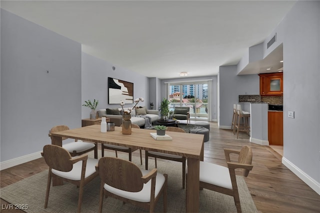 dining space featuring baseboards, light wood finished floors, and visible vents