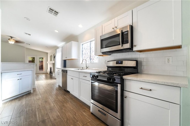 4360 Meadowlark Wing Way N, Las Vegas, NV 89084 - kitchen with appliances with stainless steel finishes, a sink, decorative backsplash, white cabinets, and vaulted ceiling