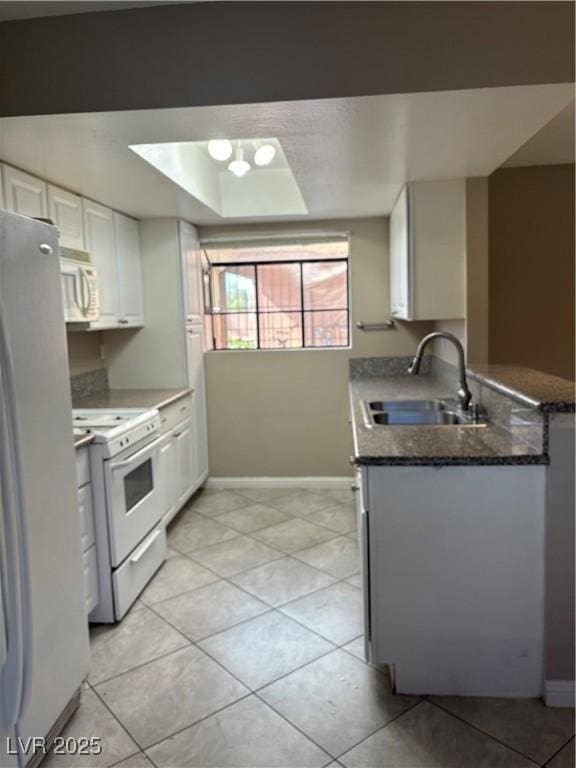 kitchen with white appliances, a sink, white cabinetry, and baseboards