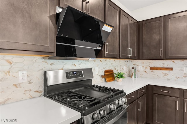 kitchen featuring ventilation hood, light countertops, stainless steel range with gas cooktop, dark brown cabinetry, and decorative backsplash