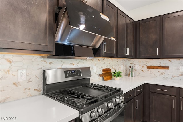 kitchen featuring under cabinet range hood, light countertops, stainless steel range with gas stovetop, dark brown cabinetry, and tasteful backsplash