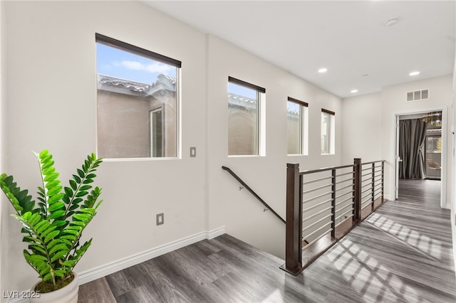 interior space with baseboards, visible vents, recessed lighting, an upstairs landing, and wood finished floors