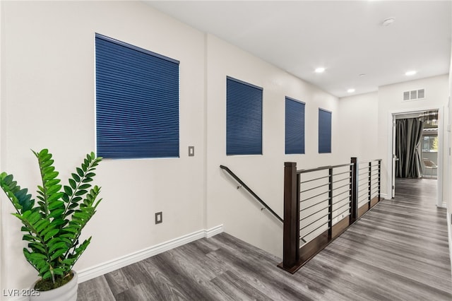 hallway with visible vents, baseboards, recessed lighting, an upstairs landing, and wood finished floors
