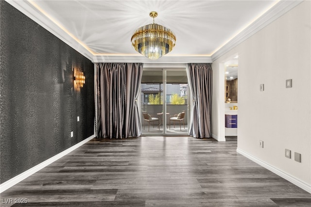 unfurnished room featuring baseboards, wood finished floors, a notable chandelier, and crown molding