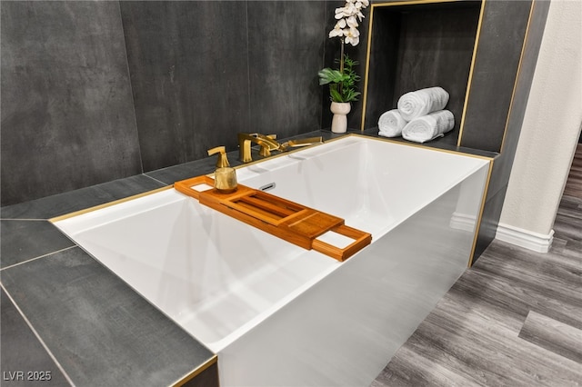 interior space featuring a tub to relax in, wood finished floors, and baseboards