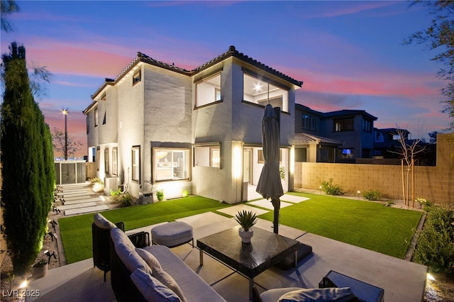 back of property at dusk featuring stucco siding, a tiled roof, a patio, and fence