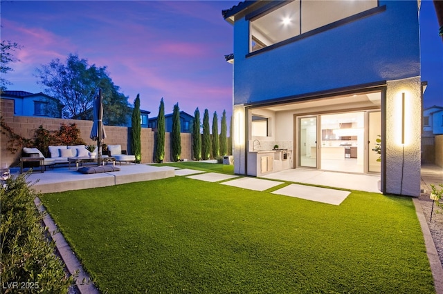 view of yard featuring outdoor lounge area, a sink, a fenced backyard, a patio, and area for grilling