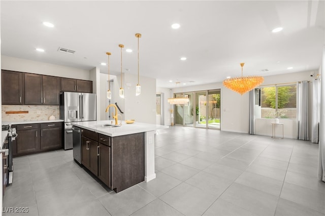 kitchen with a sink, tasteful backsplash, visible vents, dark brown cabinetry, and light countertops