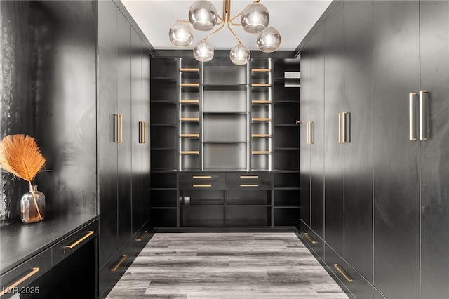 spacious closet with wood finished floors and an inviting chandelier