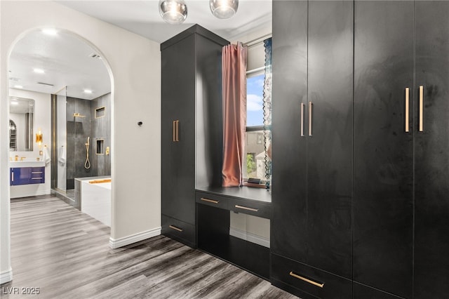 interior space with arched walkways and wood finished floors