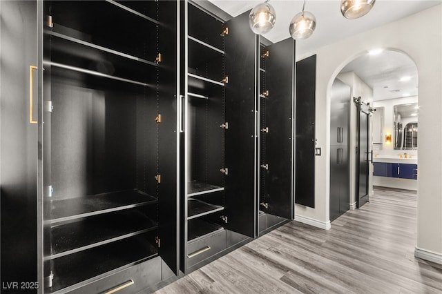 spacious closet with arched walkways and wood finished floors