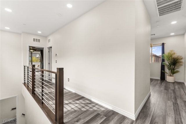 hallway with recessed lighting, wood finished floors, visible vents, and an upstairs landing