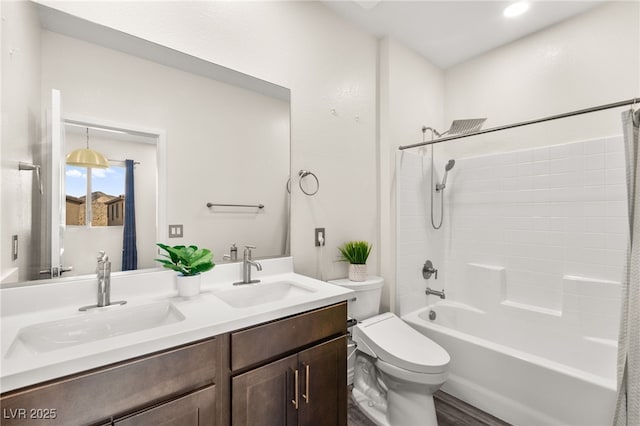 bathroom with double vanity, toilet, wood finished floors, and a sink