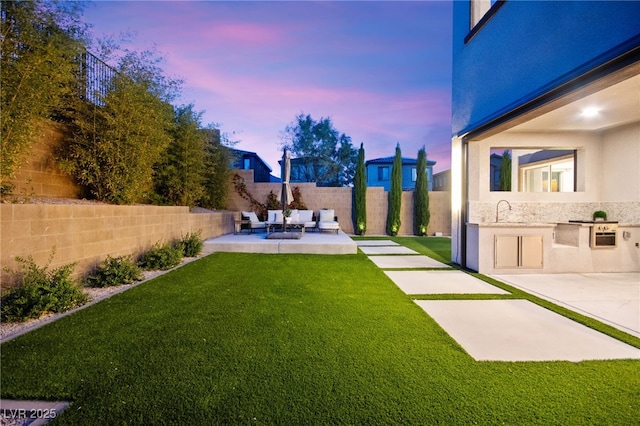 view of yard featuring a sink, a fenced backyard, area for grilling, a patio, and an outdoor hangout area