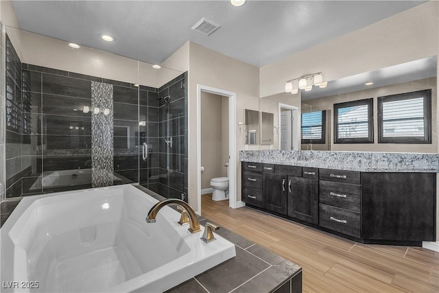 full bath featuring toilet, a garden tub, a shower stall, wood finish floors, and vanity