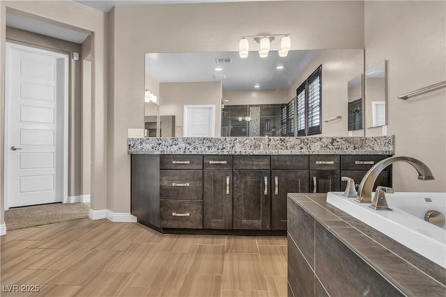 full bathroom with a shower stall, vanity, baseboards, and wood finished floors