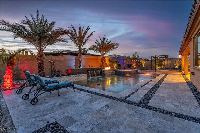 pool at dusk with a patio area, a fenced backyard, an in-ground hot tub, and a fire pit