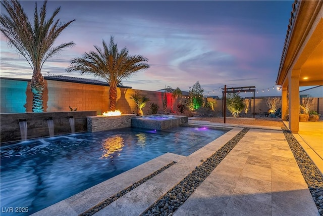 pool at dusk with a patio, a fenced backyard, a pool with connected hot tub, and a fire pit