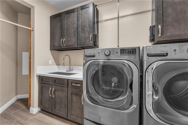 clothes washing area with washing machine and dryer, cabinet space, and baseboards