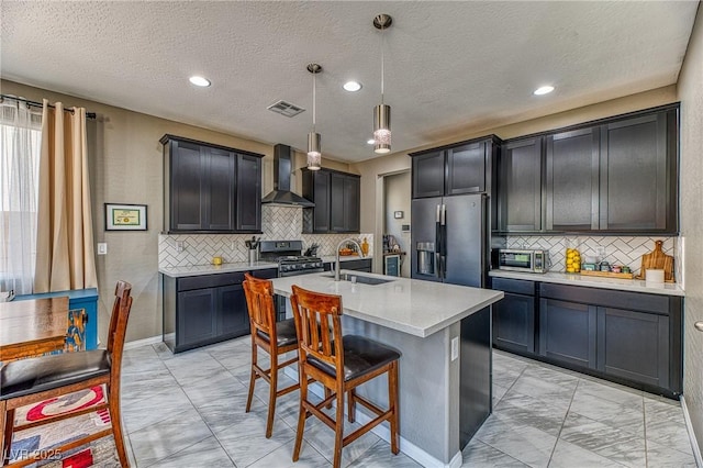 kitchen featuring wall chimney exhaust hood, a sink, visible vents, marble finish floor, and appliances with stainless steel finishes