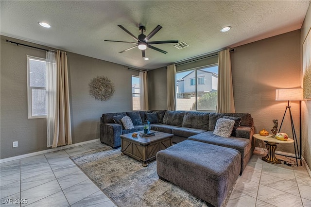 living room featuring marble finish floor, a ceiling fan, visible vents, and a healthy amount of sunlight