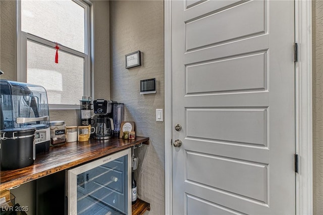 interior space featuring a textured wall, beverage cooler, and a bar