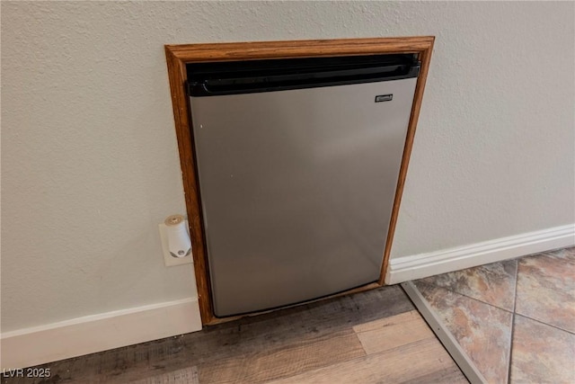 interior details with baseboards, wood finished floors, and refrigerator