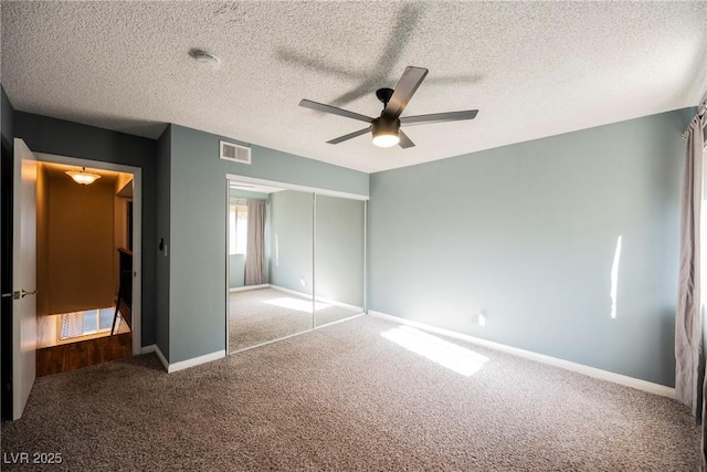 unfurnished bedroom featuring visible vents, a closet, baseboards, a textured ceiling, and carpet flooring