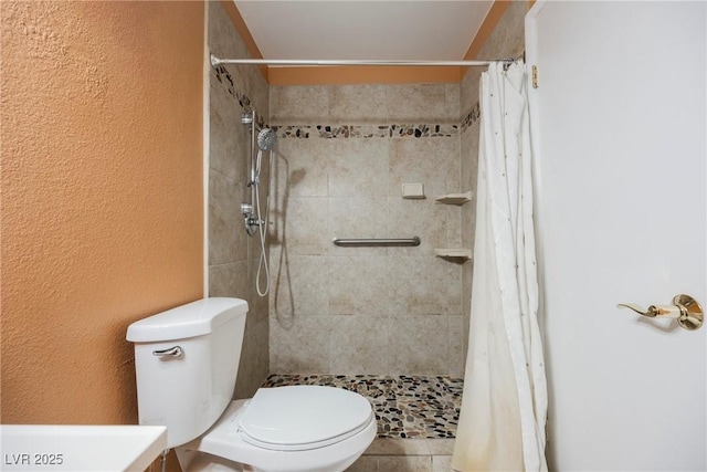 full bath with a textured wall, a tile shower, and toilet