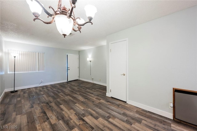 empty room with baseboards, wood finished floors, and an inviting chandelier