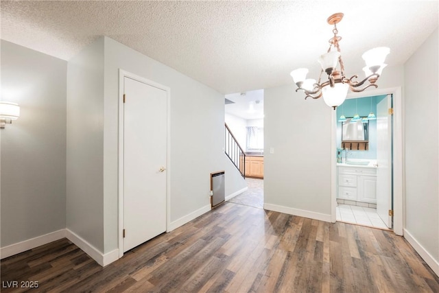 unfurnished dining area with stairway, an inviting chandelier, wood finished floors, and a sink