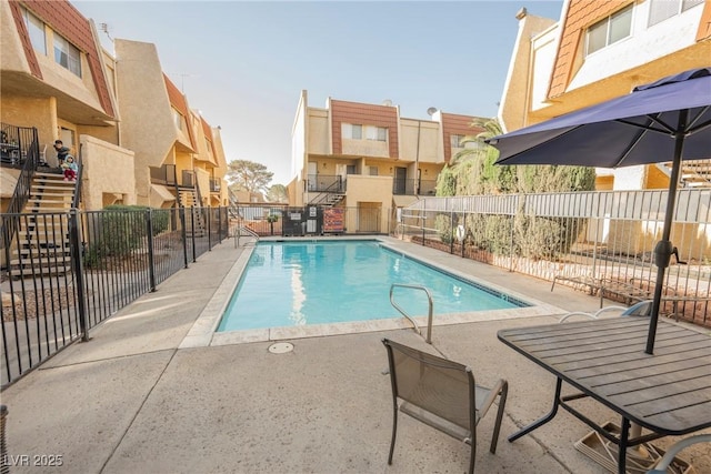 pool with a patio area, fence, and a residential view