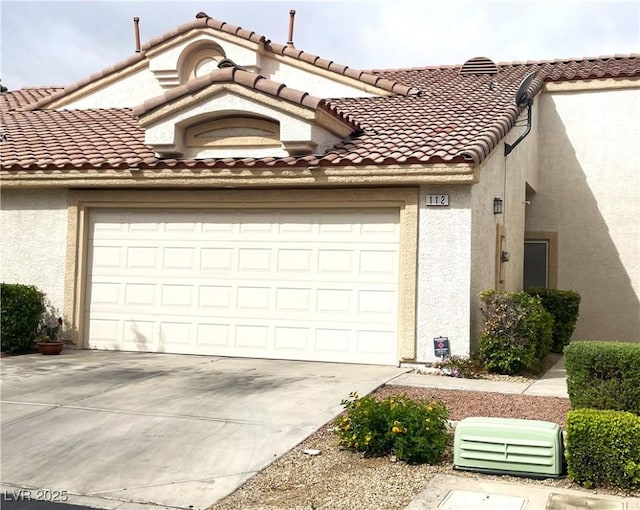 view of front of home featuring stucco siding, a tiled roof, driveway, and a garage