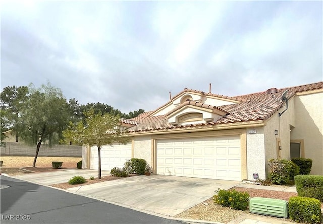 view of front facade with fence, concrete driveway, stucco siding, a tile roof, and a garage