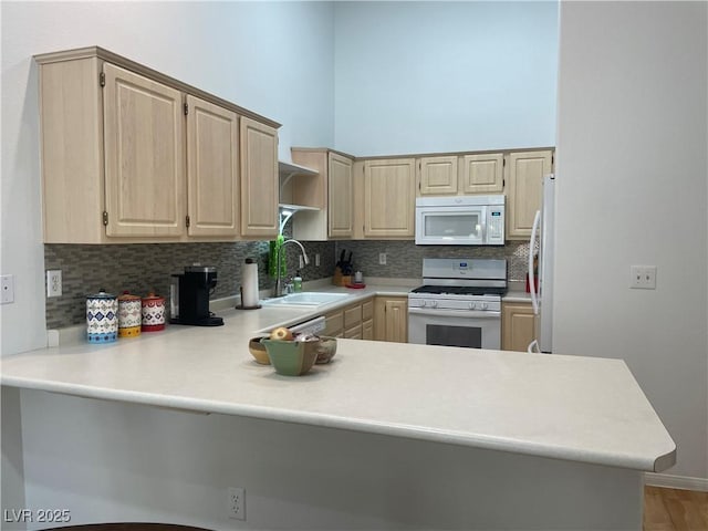 kitchen featuring light brown cabinets, a sink, white appliances, backsplash, and a peninsula