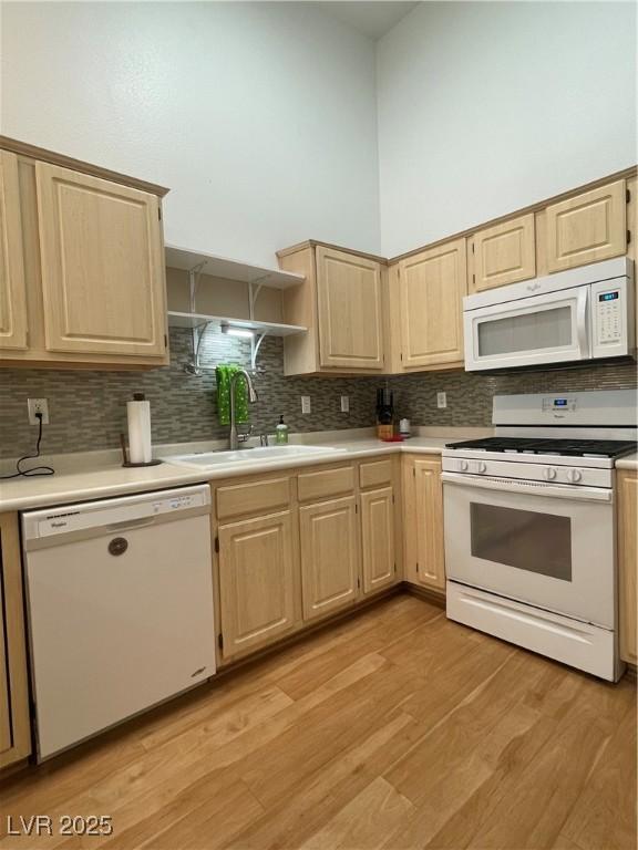 kitchen featuring a sink, decorative backsplash, white appliances, light brown cabinets, and light countertops