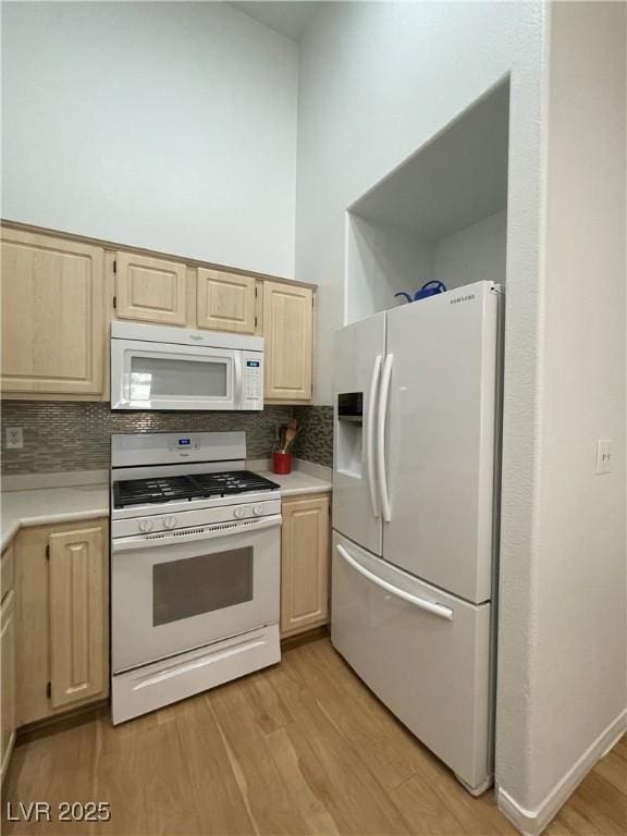 kitchen featuring tasteful backsplash, light brown cabinetry, white appliances, light wood finished floors, and light countertops