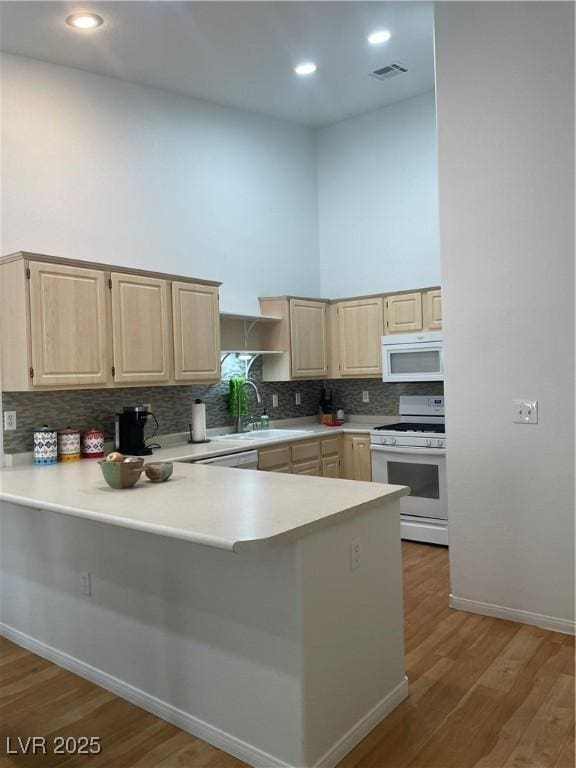 kitchen with visible vents, a towering ceiling, white appliances, and light brown cabinetry