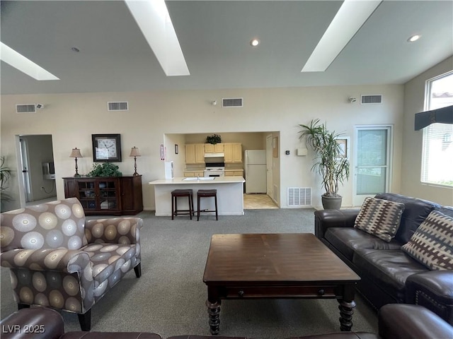 living room with visible vents, a skylight, and light carpet