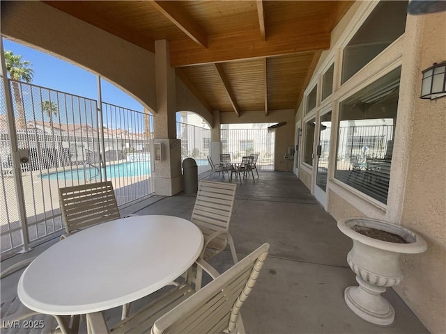 view of patio with fence, a community pool, and outdoor dining space