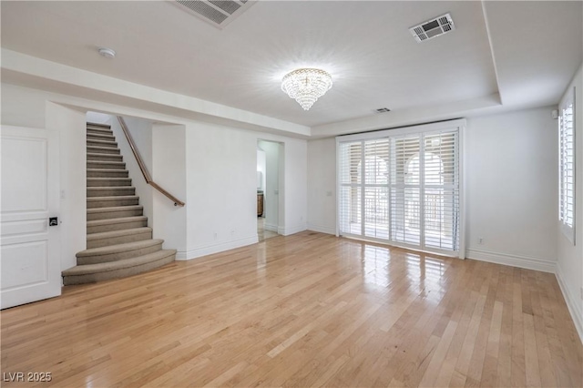 unfurnished living room featuring an inviting chandelier, visible vents, baseboards, and stairs