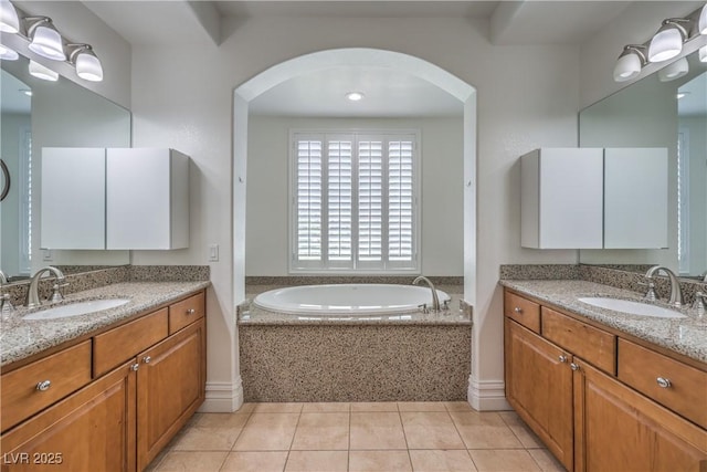 bathroom with a garden tub, two vanities, a sink, and tile patterned floors